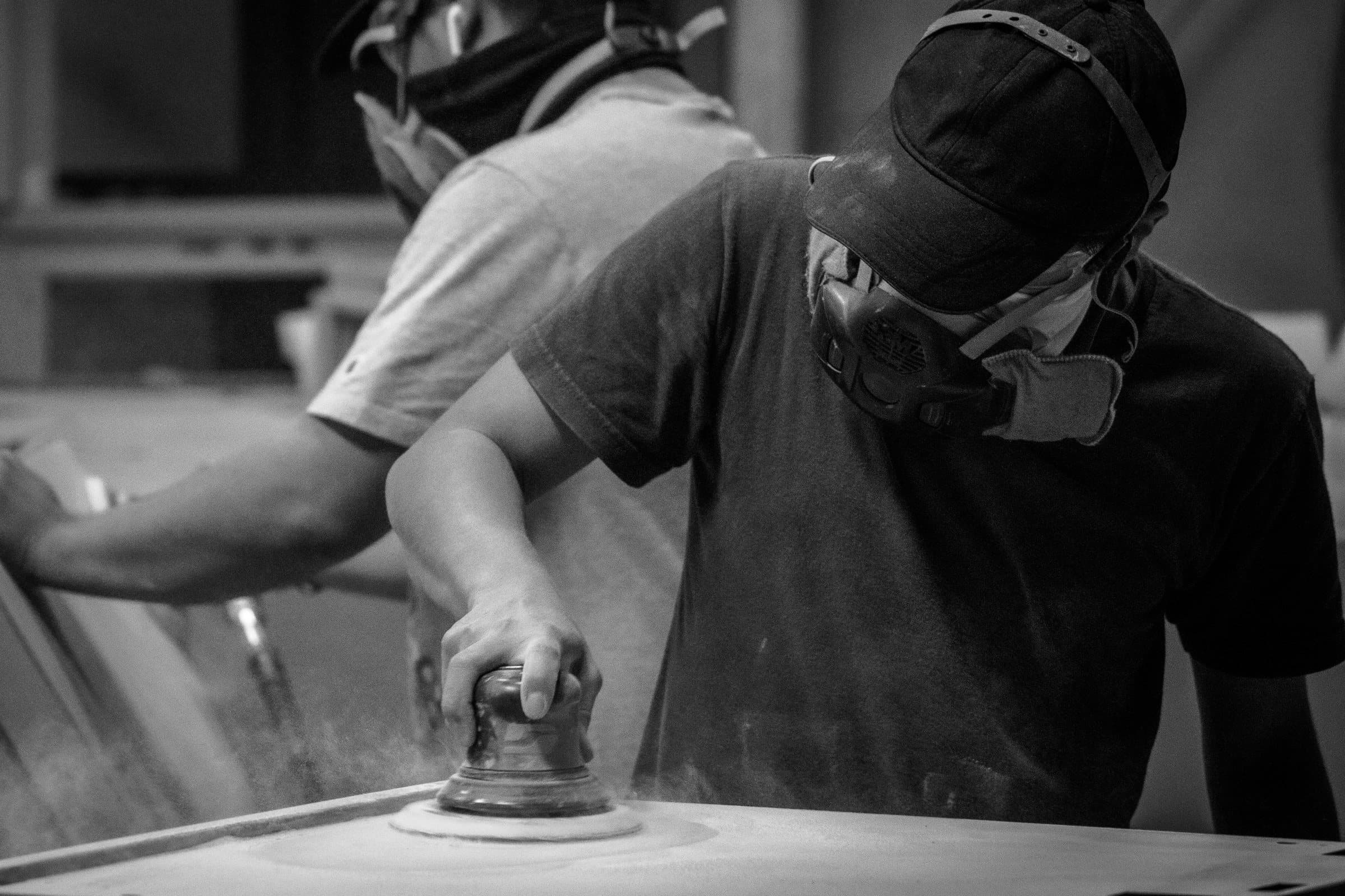 Fabricator finishing a formed panel with an orbital sander